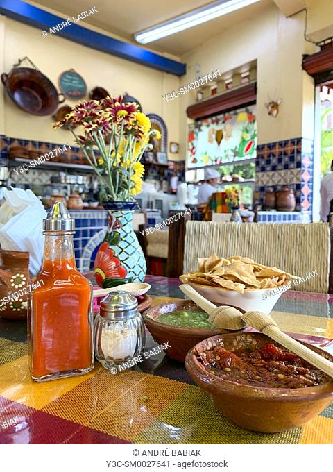 Table setting with salsas and taco chips, and flowers in a Mexican restaurant