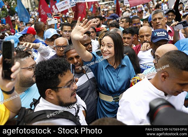23 June 2023, Venezuela, Caracas: Corina Machado (M) waves to supporters as she arrives surrounded by supporters at Plaza Altamira for the announcement of her...