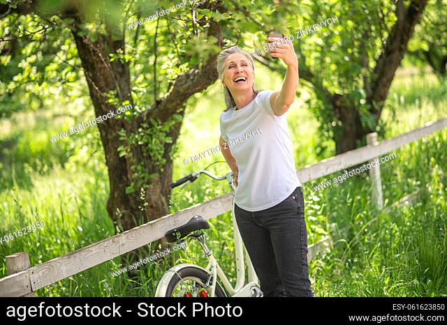 Selfie in a park. A woman with a bike making selfie and smiling