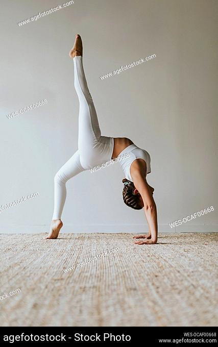 Flexible yogi practicing Eka Pada Urdhva Dhanurasana on carpet at health club