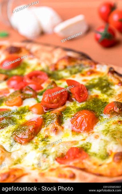 Italian pizza with cherry tomatoes, pesto sauce basil and mozzarella cheese baked in a wood oven. Italian cuisine