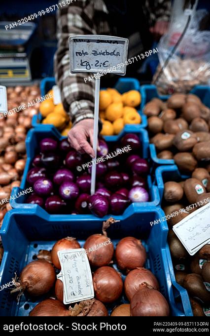 09 April 2022, North Rhine-Westphalia, Oberhausen: Lydia Mosters puts a price tag for onions in the display at the weekly market in Oberhausen-Sterkrade
