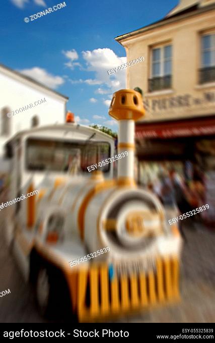 Abstract background. Small train for tourists stops in front of souvenir stores. Blur effect defocusing filter applied, with vintage instagram look