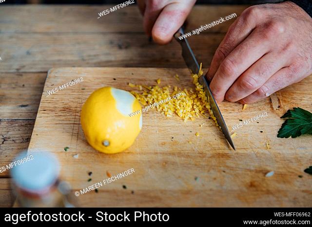 Close-up of chef cutting lemon peel on cutting board in kitchen
