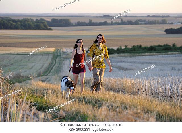 couple of young people walking with a dog around Mittainville, Yvelines department, Ile-de-France region, France, Europe