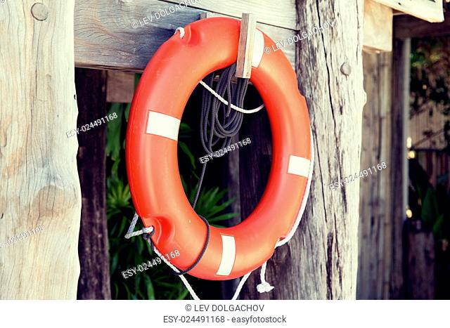 summer, beach, swimming and life saving concept - lifebuoy or life preserver hanging on rescue booth