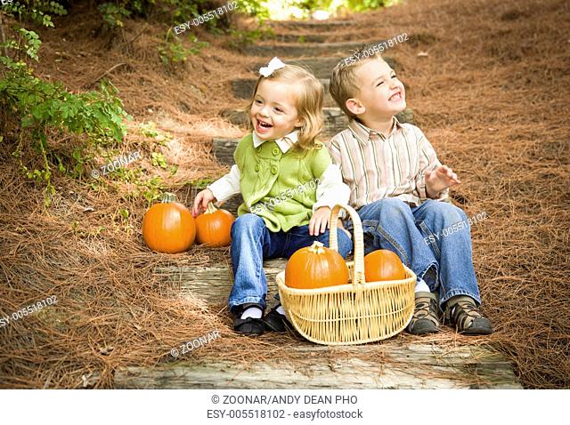 Two Children Sitting on Wood Steps with Pumpkins