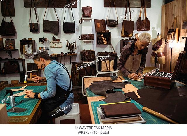Attentive craftswoman hammering leather