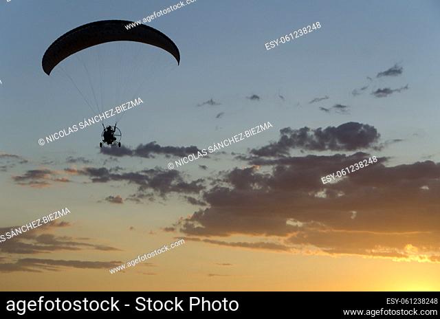 Silhouette of an ultralight flying at sunset