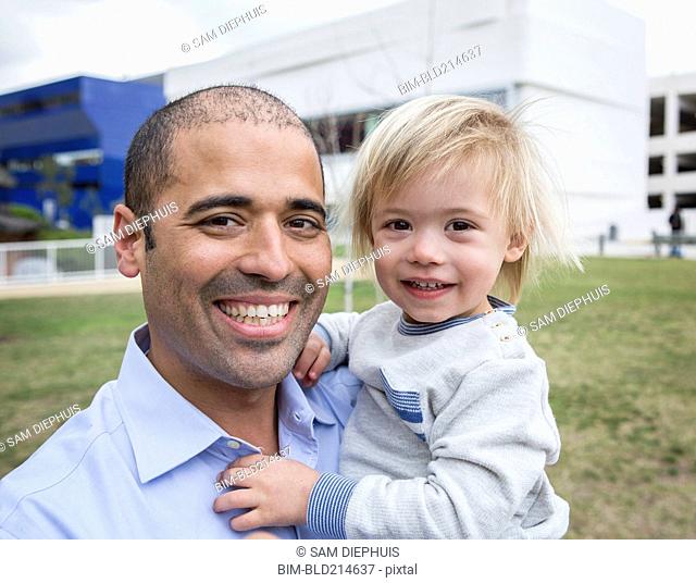 Hispanic father and son smiling in field