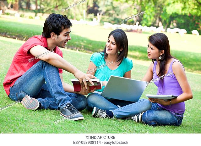 Group of three friends sitting in lawn