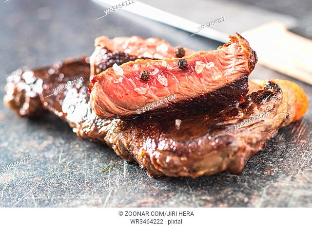 Sliced medium rare grilled steak on old kitchen table