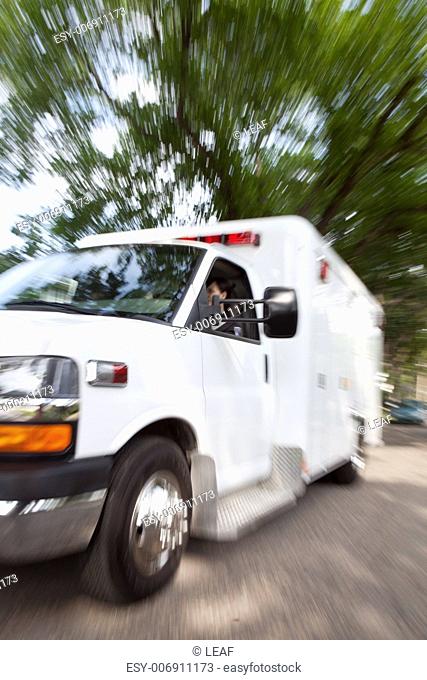Motion blur of ambulance speeding with female paramedic driving