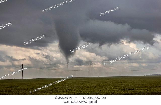 A very large funnel cloud sits feet off the ground, threatening a tornado is imminent