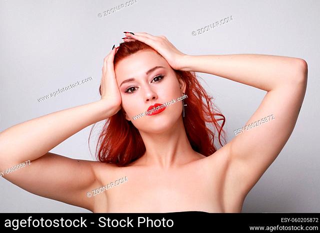 Young woman with red hair posing over grey background. High quality photo