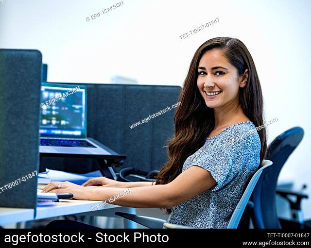 Portrait of smiling woman sitting at desk in office