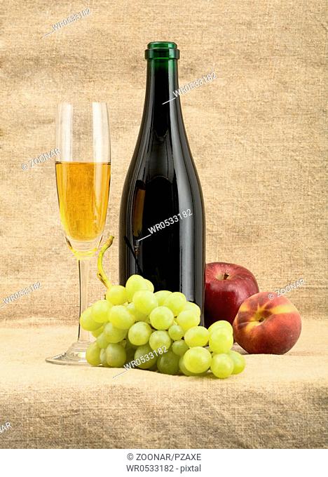 Champagne bottle, goblet, grapes, apple and peach