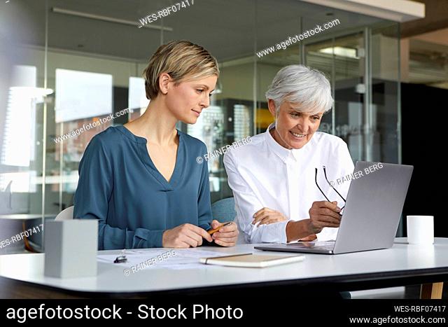 Two businesswomen working together with laptop in office