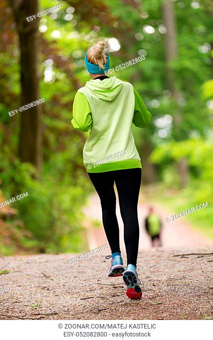 Sporty young female runner in forest. Running woman. Female runner during outdoor workout in nature. Fitness model outdoors. Weight Loss