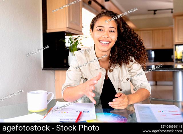 Portrait of smiling biracial businesswoman on video call telecommuting from home office