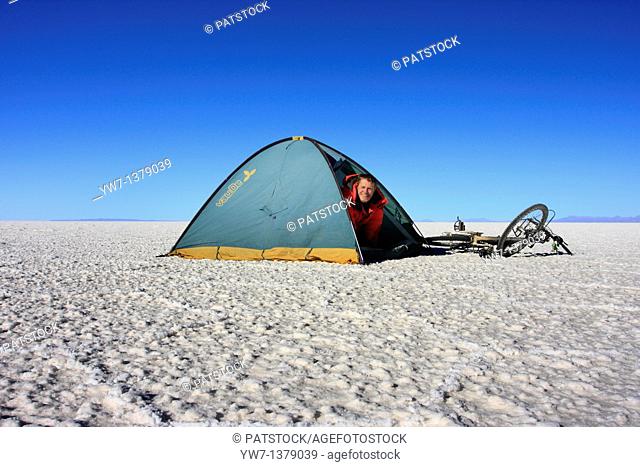 A biker in a tent on the frozen salt lake called 'Salar de Uyuni' in Bolivia