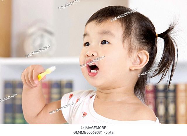 Little girl holding tooth brush and looking away