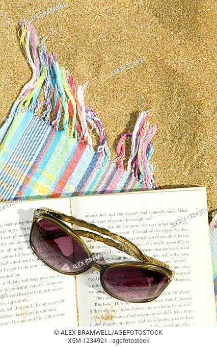 Sunglasses and novel on a beach towel