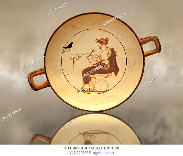 White Ground Kylix from a tomb in Delphi. Athenian 480-470 BC. Apollo depicted crowned in Myrtle Leaves, seated on a stool, with lion claw feet