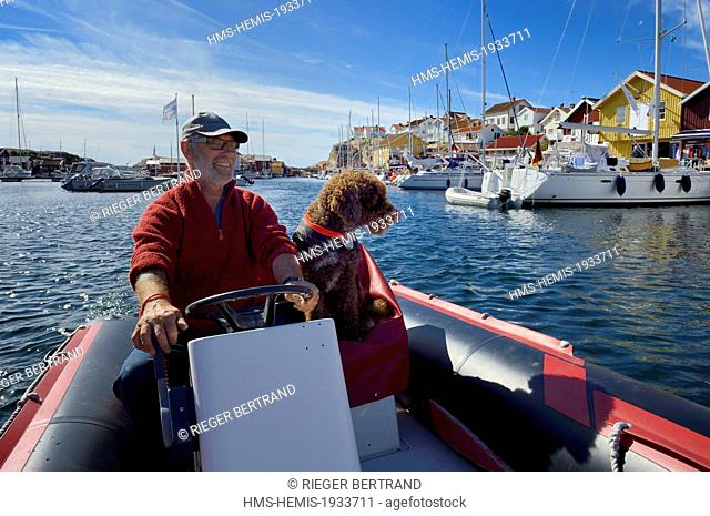 Sweden, Vastra Gotaland, Smogen harbour, Cyril and his dog Simpson aboard his zodiac