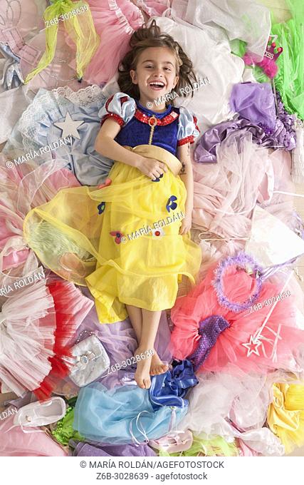 Little girl dressed up like SnowWhite and surrounded by many little girl's princess costumes