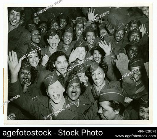 A crowd of African American Women's Army Corps members waving at the camera, Staten Island Terminal, New York Port of Embarkation. United States
