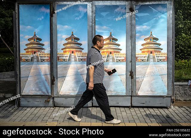 A man walks past posters depicting the Temples of Heaven in Beijing, China on 13/09/2021 by Wiktor Dabkowski. - Beijing/Hebei/China