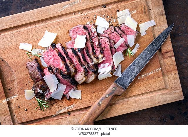 Traditional Italian Tagliata Steak with Parmesan as close-up on cutting board