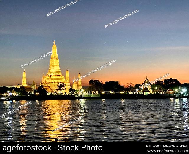 30 January 2022, Thailand, Bangkok: Wat Arun, the Temple of Dawn, seen from across the Chao Phraya River. The temple is imposingly illuminated in the evening