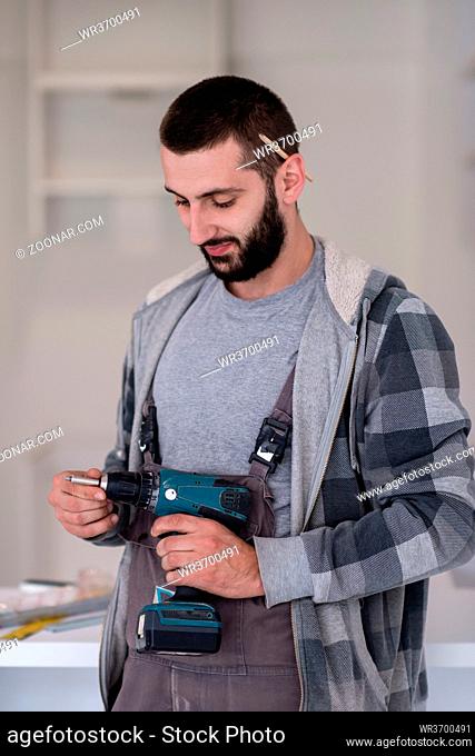 young professional worker preparing a hand drilling machine while installing a new stylish modern kitchen furniture