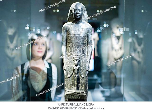04 December 2019, Rhineland-Palatinate, Speyer: A woman looks at an Egyptian healing statue from the 4th century BC in the Historical Museum of the Palatinate...