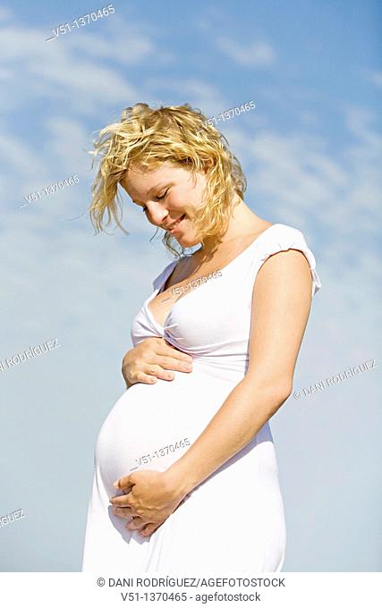 Blonde pregnant woman enjoying her pregnancy at the beach