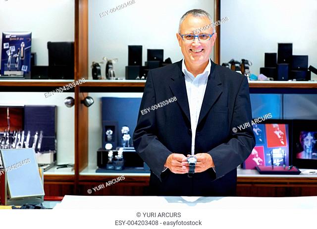Mature jewllery store clerk smiling while holding a wristwatch - portrait