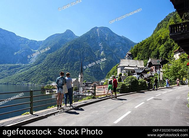 Tourist take photos at the view on Hallstatt town and the lake Hallstatter See on Traun River, June 29, 2023. Sign „ACHTUNG, WIR WOHNEN HIER!“ „ATTENTION