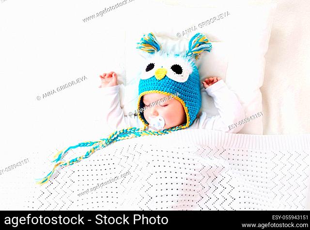 seven month old boy sleeping in the bed in owl hat