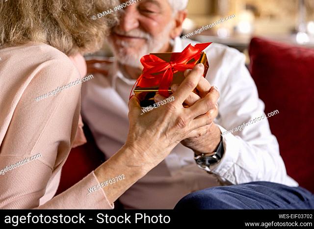 Senior man and woman holding gift at boutique hotel
