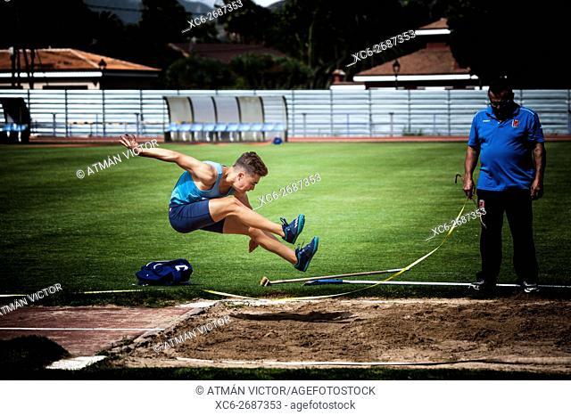 sports boy performing long jump on an athletic piste