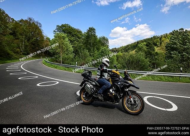 17 May 2023, North Rhine-Westphalia, Hürtgenwald: A motorcyclist rides through a switchback with circles painted on the roadway near Vossenack