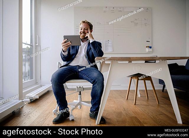 Smiling businessman using tablet in office