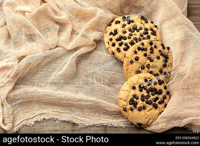 round cookies with pieces of chocolate on a textile towel, a stack of pastries
