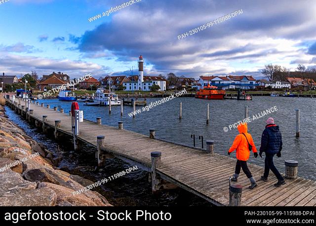 05 January 2023, Mecklenburg-Western Pomerania, Timmendorf (poel): Walkers are in the small fishing port in Timmendorf on the Baltic Sea island of Poel