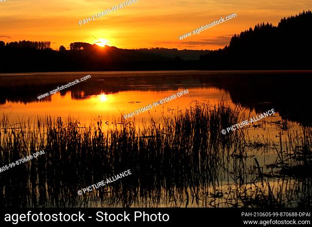 05 June 2021, Saxony-Anhalt, Elend: The light of the rising sun is reflected in the waters of the Mandelholz dam. The temperatures rise again to over 20 degrees...