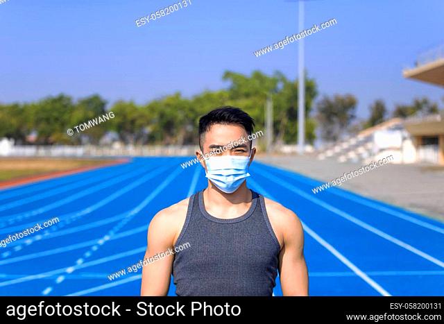 Man in medical mask standing on track and ready to run