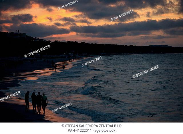 Holiday-makers walk along the beach in the light of the setting sun in Binz on Ruegen, Germany, 22 July 2013. Tourism is the main economic sector on Ruegen