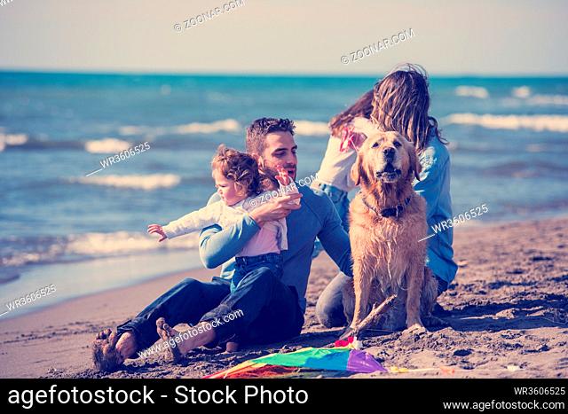 happy young family with kids having fun with a dog and kite at beach during autumn day filter